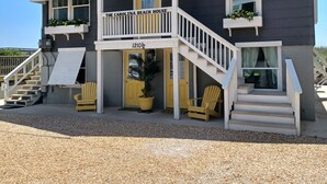 A two-story building with a balcony, a yellow door, and a sign reading "The Carolina Beach House".