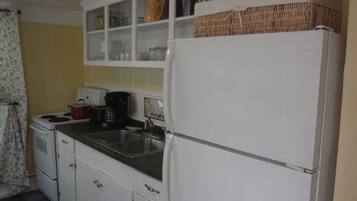 A compact kitchen with white cabinets, a refrigerator, a stove, and a sink.