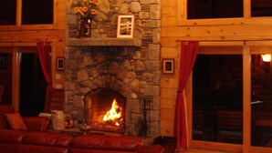 A cozy living room with a stone fireplace, leather sofa, and large windows. - Privacy and Luxury on 9 acres Overlooking Ponds & Ocean - Dog Friendly (Provincetown)
