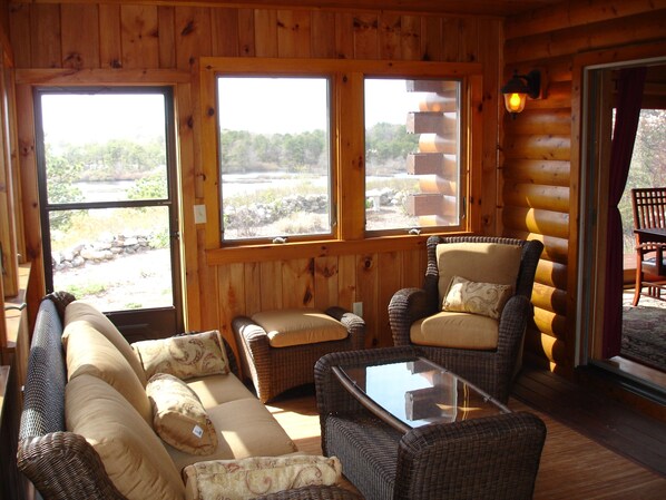 A log cabin interior with a sofa, two armchairs, and a coffee table. - Privacy and Luxury on 9 acres Overlooking Ponds & Ocean - Dog Friendly (Provincetown)