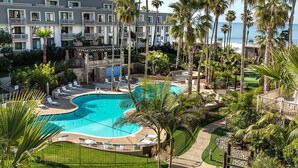 A resort with a large pool, palm trees, and a view of the ocean.