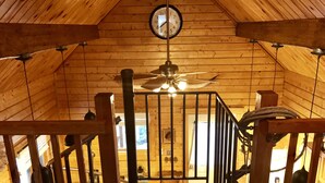 Ein Holzinnenraum mit Holzbalkendecke, Deckenventilator und einer Wanduhr.