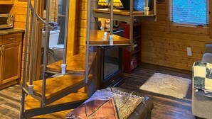 Ein Holzblockhaus-Interieur mit Wendeltreppe, Küchenzeile und einem gemütlichen Wohnbereich.