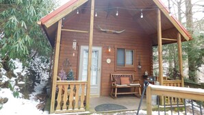 Eine Holzhütte mit Veranda, einer Bank und einer Tür.