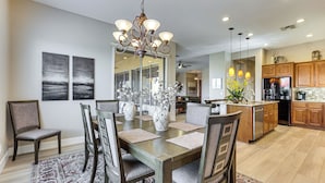 A spacious dining area with a wooden table, chairs, and a chandelier. - Pool, Hot Tub & Golf Course View! ‘Anthem Oasis’ (Anthem)
