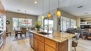 A spacious kitchen with a large island, wooden cabinets, and pendant lighting. - Pool, Hot Tub & Golf Course View! ‘Anthem Oasis’ (Anthem)