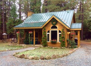 A rustic cabin with a green metal roof, wooden walls, and a front porch with a bench. - 2 Bedroom Cabin  (Alta)