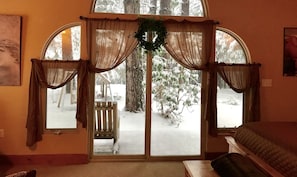 A main bedroom with large arched windows, a wooden bench outside, and a wreath on the windowsill. - 2 Bedroom Cabin (Alta)