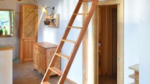 A wooden interior with a lofted sleeping area, a ladder, and a kitchen with wooden cabinets. - CHALET BRENTA DOLOMITES (Madonna di Campiglio)