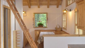 A wooden interior with a kitchen area, a staircase, and a window with a view of greenery. - CHALET BRENTA DOLOMITES (Madonna di Campiglio)