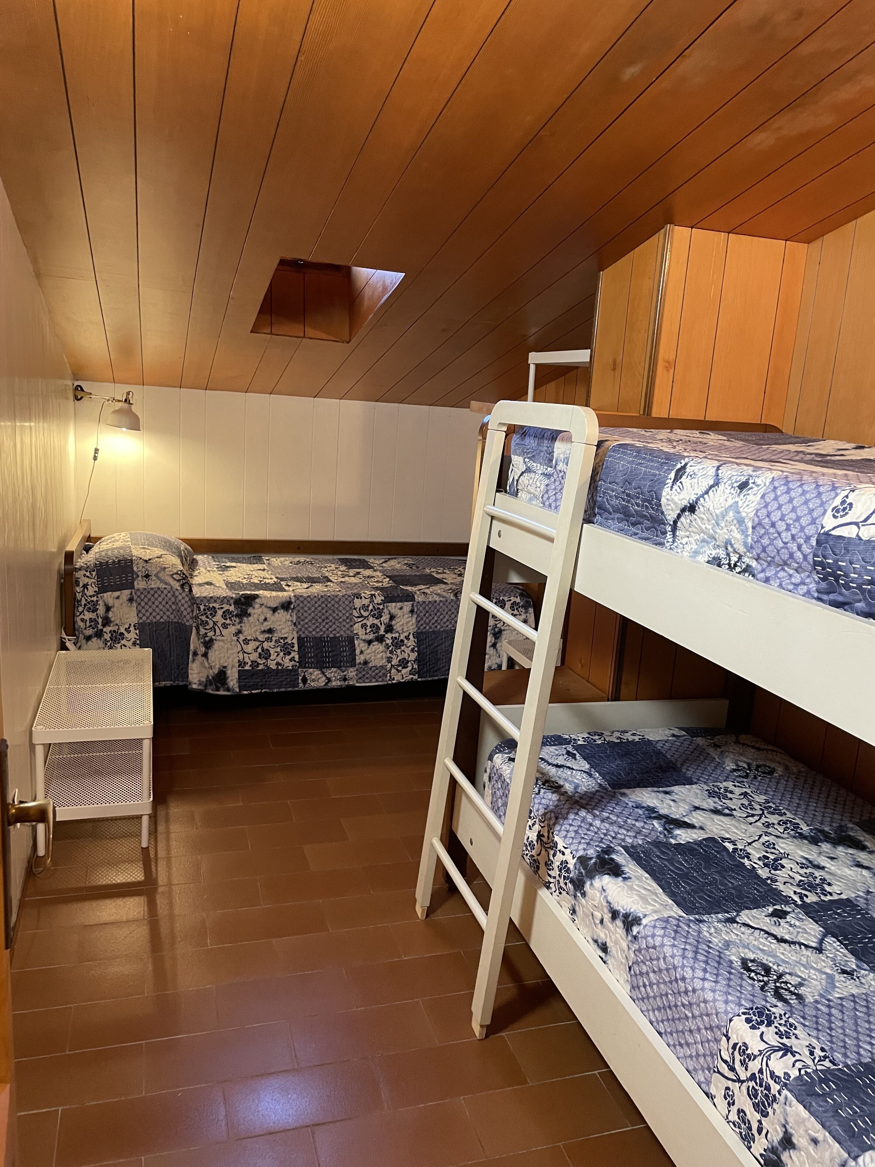Habitació amb lliteres, sostre de fusta i una taula petita.