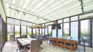 Un patio soleado con una mesa de comedor, sillas y un televisor.