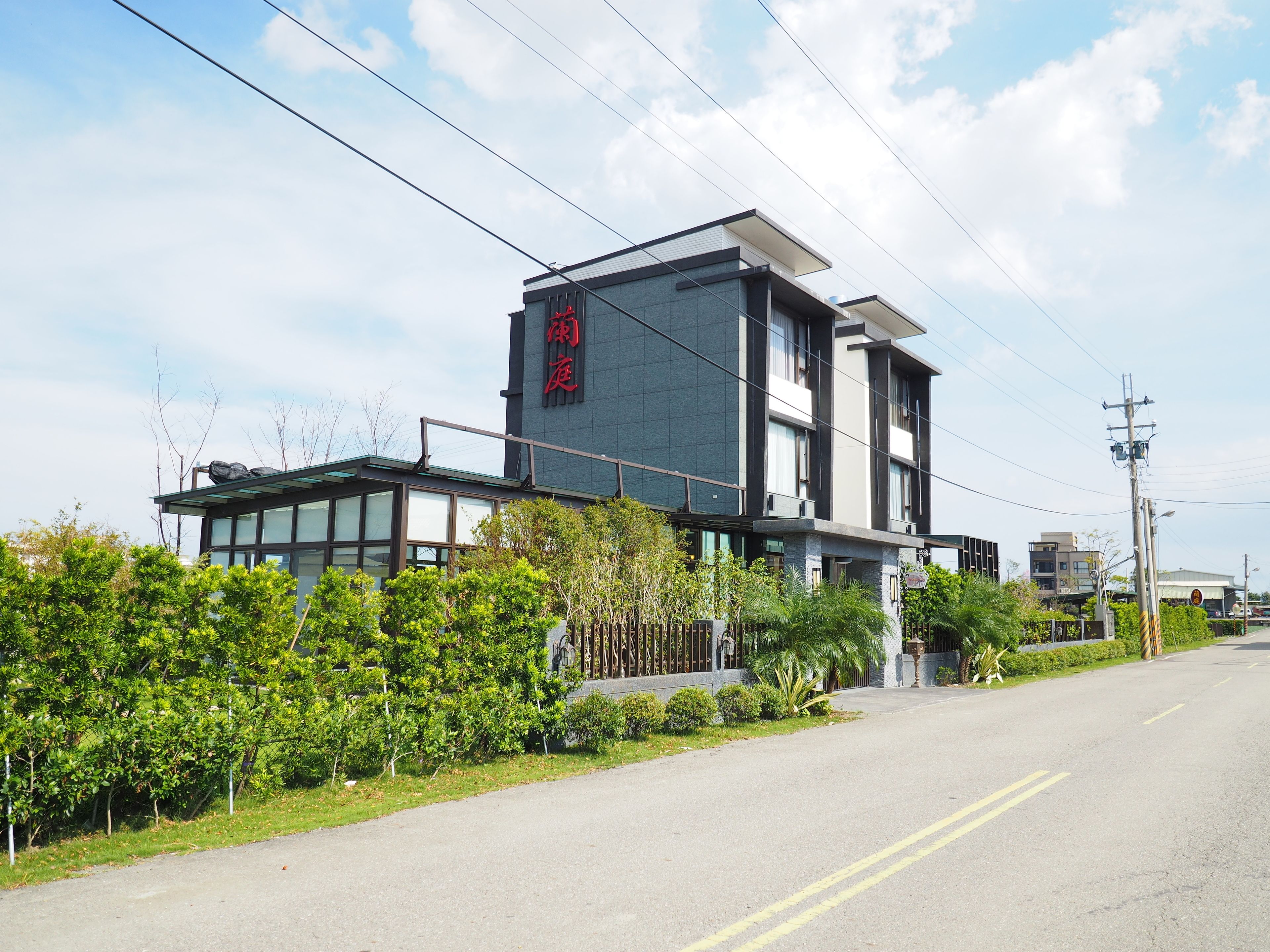 A modern building with a prominent sign, surrounded by greenery and a clear sky.