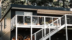 Una casa moderna con un balcone, una scala e un'ampia finestra.