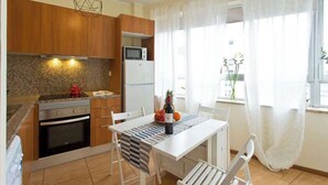 Een moderne keuken met houten kastjes, een inbouwoven, een magnetron en een eethoek met een tafel en stoelen.