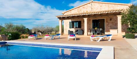 Enjoy a pool surrounded by a patio with lounge chairs and a table.