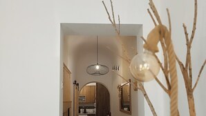 Un couloir menant à une cuisine, avec un luminaire suspendu et des miroirs fixés au mur.