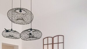 Un salon moderne avec un canapé noir, des coussins décoratifs, une lampe sur pied et un luminaire fixé au mur.