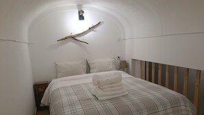 Une chambre à coucher avec un lit, des oreillers, une lampe et une branche décorative accrochée au mur.