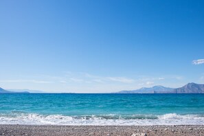 A clear view of a beach with a rocky shoreline and calm sea.