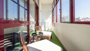 Un balcon avec vue sur la ville, une petite table avec une chaise et une plante en pot.