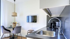 Eine moderne Küche mit einer großen Spüle, einem an der Wand befestigten Flachbildfernseher und einem Essbereich mit zwei Stühlen und einem kleinen Tisch.