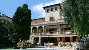 A two-story building with a pool, outdoor seating, and potted plants.