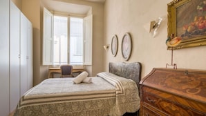 A bedroom with a bed, a dresser, a desk, and a window with shutters. - Tornaquinci Luxury Penthouse (Firenze)