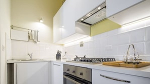 A modern kitchen with white cabinets, a built-in oven, a gas stove, and a countertop with glassware. - Tornaquinci Luxury Penthouse (Firenze)