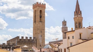 A historic tower with a crenellated top and a smaller adjacent tower with a spire. - Tornaquinci Luxury Penthouse (Firenze)