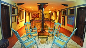 A hallway with four blue rocking chairs, a staircase, and a fire extinguisher. - Hotel Los Balcones De Chinandega (Chinandega)