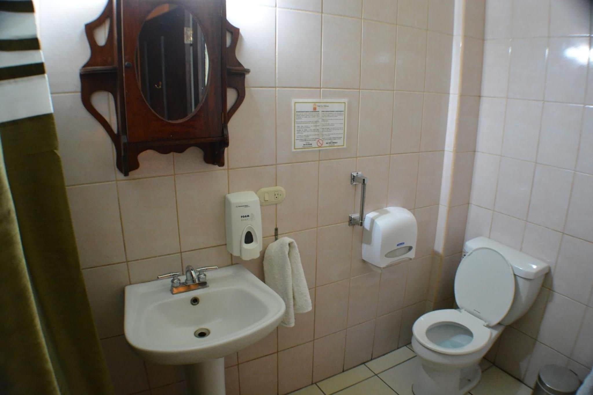 Baño con lavamanos, inodoro y espejo.