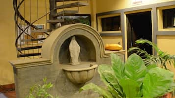 Una escalera en espiral, una fuente y plantas en macetas en un vestíbulo.