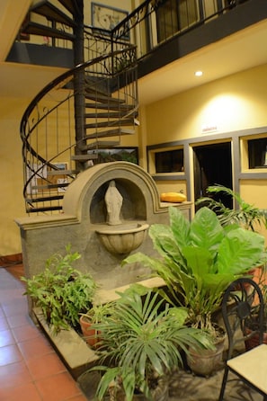 A spiral staircase, a fountain, and potted plants in a lobby area. - Hotel Los Balcones De Chinandega (Chinandega)