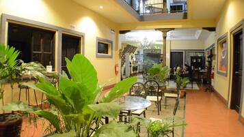 A multi-level indoor space with a dining area, seating arrangements, and a staircase leading to an upper level.