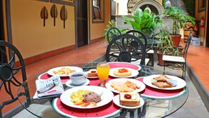 A dining area with a glass table, red placemats, and various breakfast items. - Hotel Los Balcones De Chinandega (Chinandega)
