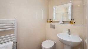 A bathroom with a white toilet, a white sink, and a mirror above the sink. There are toiletries on the sink counter. - Hot tub, spa-like garden, log burner (Chatton)
