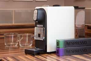 Eine Kaffeemaschine mit zwei Nespresso-Kapseln auf dem Tisch.