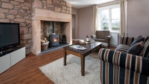 A living room with a stone fireplace, a television, a sofa, and a coffee table. - Hot tub, spa-like garden, log burner (Chatton)