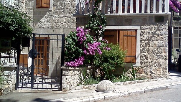 A stone building with wooden shutters, a balcony with purple flowers, and a gate. - Authentic Stone Villa In The Heart Of Split, Next To Diocletian's Palace  (Split)