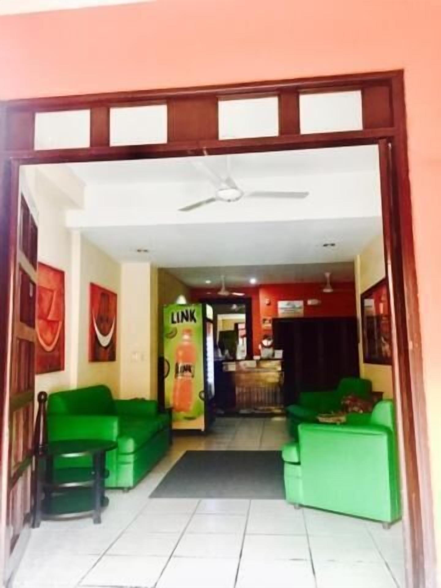A hotel lobby with green sofas, a reception desk, and a Link beverage machine.
