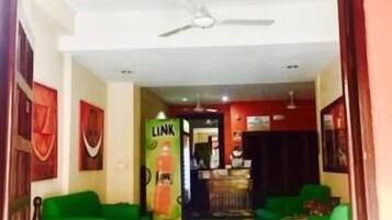 A hotel lobby with green sofas, a reception desk, and a Link beverage machine.