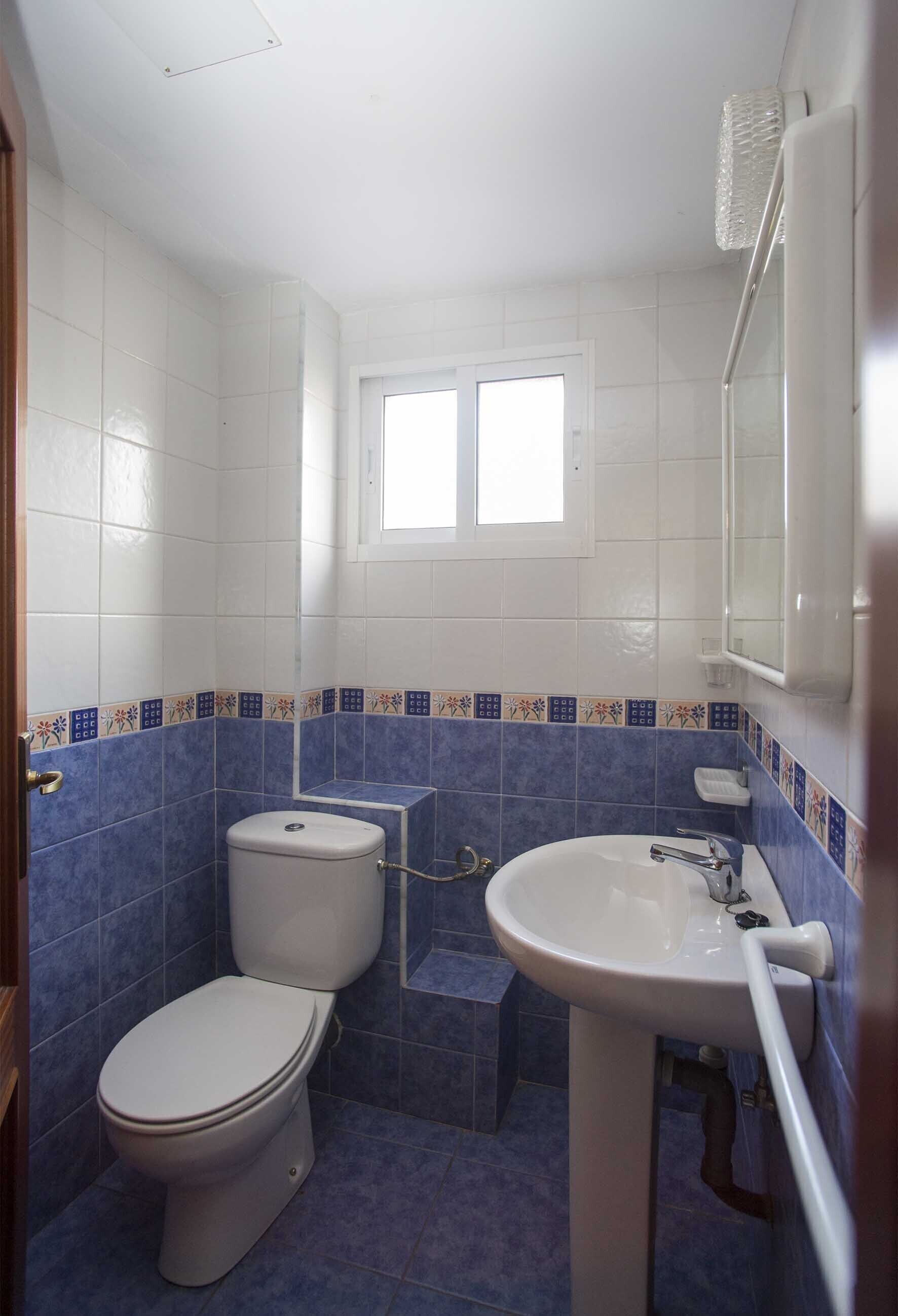 A small bathroom with a toilet, sink, and window.