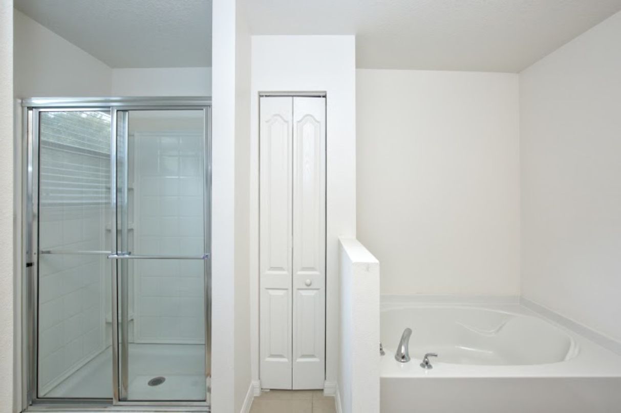 A bathroom with a glass shower enclosure, a white door, and a bathtub.