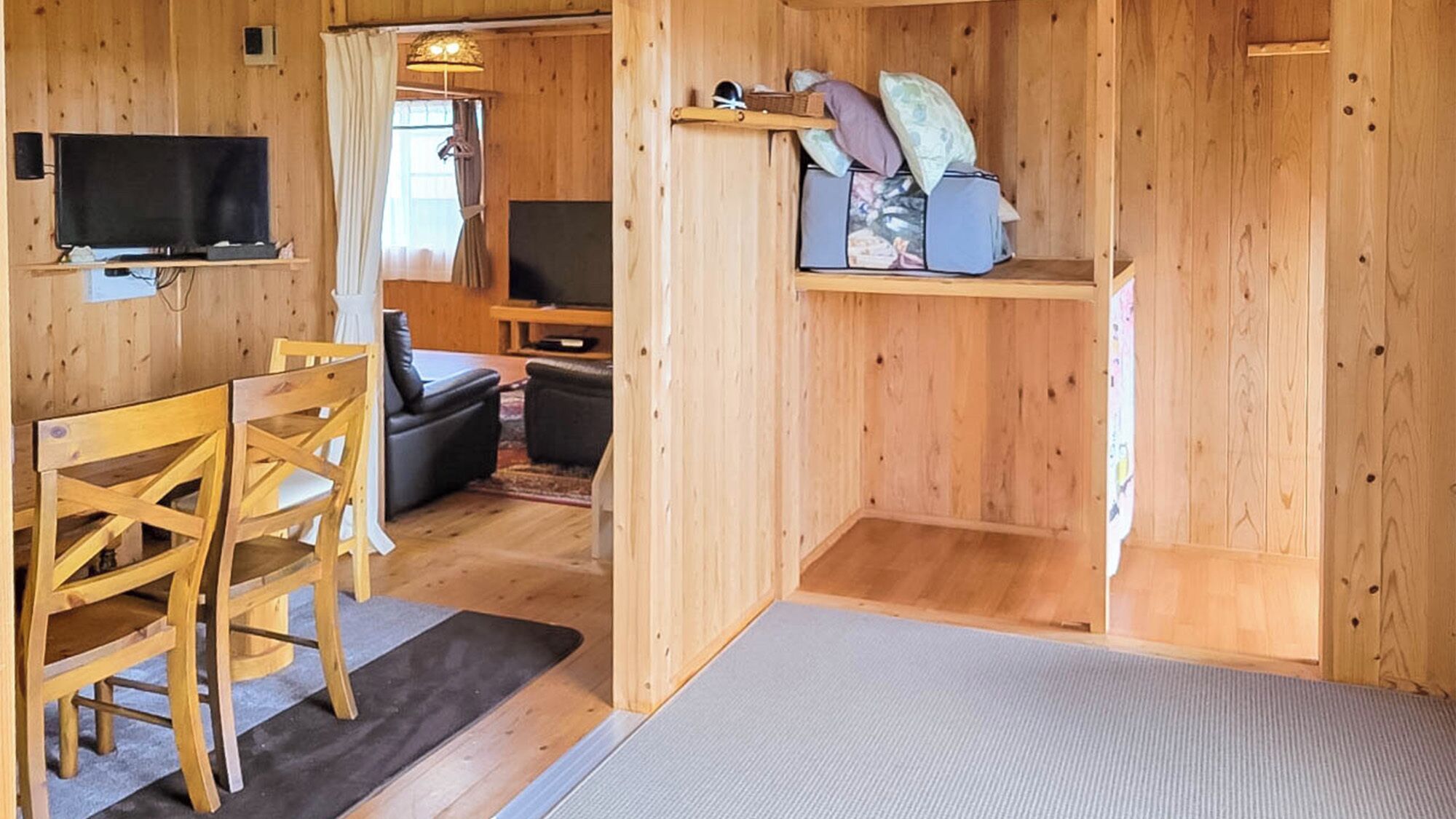 A wooden interior with a TV, a dining table with chairs, and a sofa.