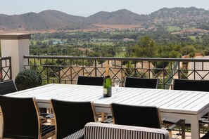 Una terrazza con un tavolo apparecchiato per due, affacciata su un paesaggio pittoresco con colline e un lago.