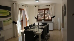A dining area with a table set for six, a window with curtains, and a wall-mounted clock. - Beautiful Detached Spacious Villa, Amazing views, Private Heated Pool, WiFi, A/C (La Manga Club)