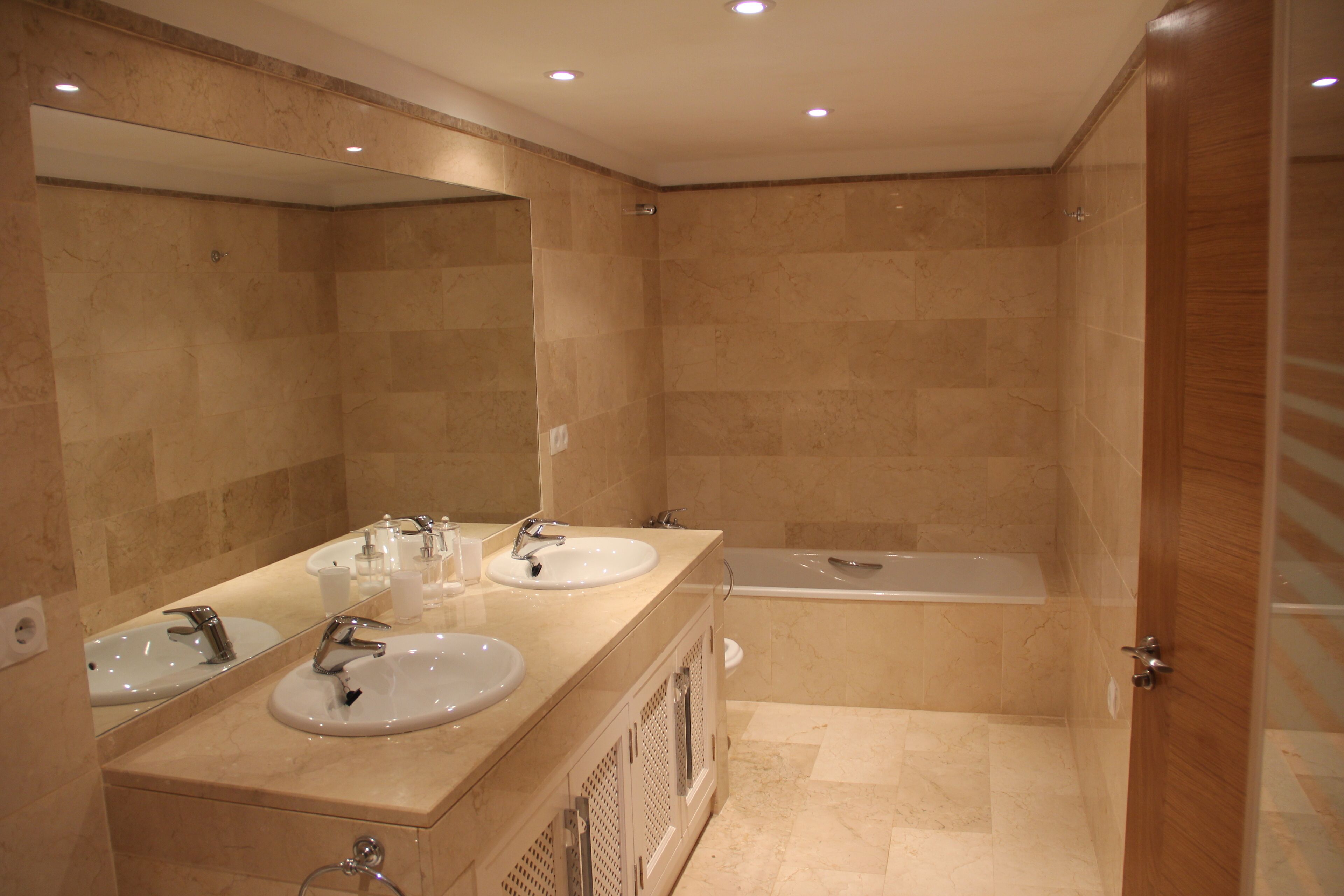 Ein modernes Badezimmer mit zwei Waschbecken, einem großen Spiegel und einer Badewanne.
