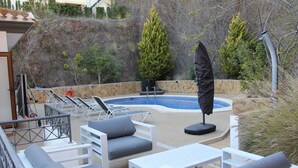 An outdoor pool area with lounge chairs, a table, and an umbrella. - Beautiful Detached Spacious Villa, Amazing views, Private Heated Pool, WiFi, A/C (La Manga Club)