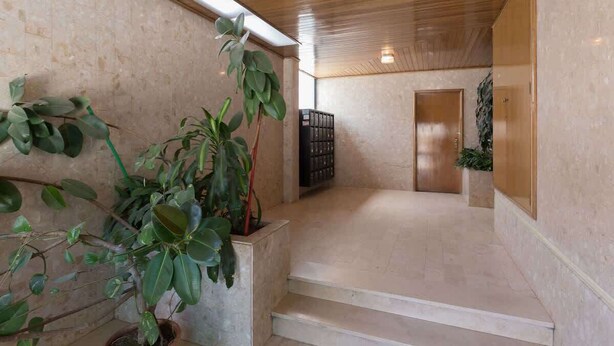 A spacious interior with a wooden ceiling, a staircase, and potted plants. - Downtown Lovely Flat by HostWise (Porto)